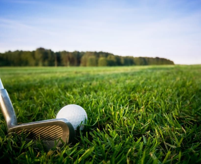 Golf ball and club on the grass ready to swing